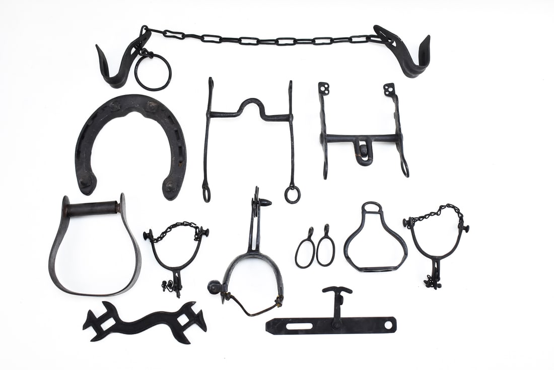 ASSORTMENT OF ANTIQUE CAST IRON EQUESTRIAN ITEMS & FARM TOOLS: A large assortment of cast iron equestrian items and other various items including a horseshoe, bits, stirrups, a harvester's wrench, and more. Circa late 19th -early 20th century. The horseshoe