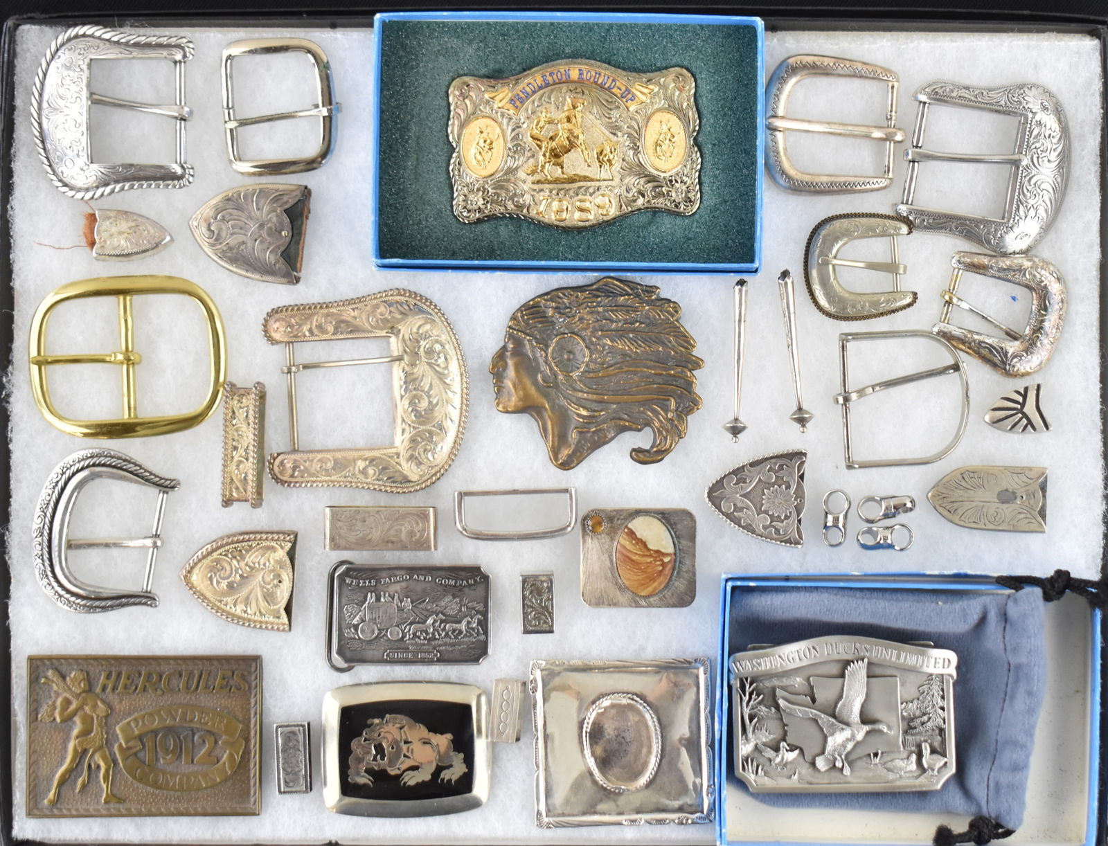 LARGE ASSORTMENT OF BELT BUCKLES, LOOPS, TIPS INCLUDING PENDLETON ROUND-UP: A large assortment of belt buckles, belt loops, belt tips, and bolo tips. Many of the pieces are marked Sterling Silver Overlay. Includes a 1989 Pendleton Round-Up belt buckle, a Hercules belt buckle,