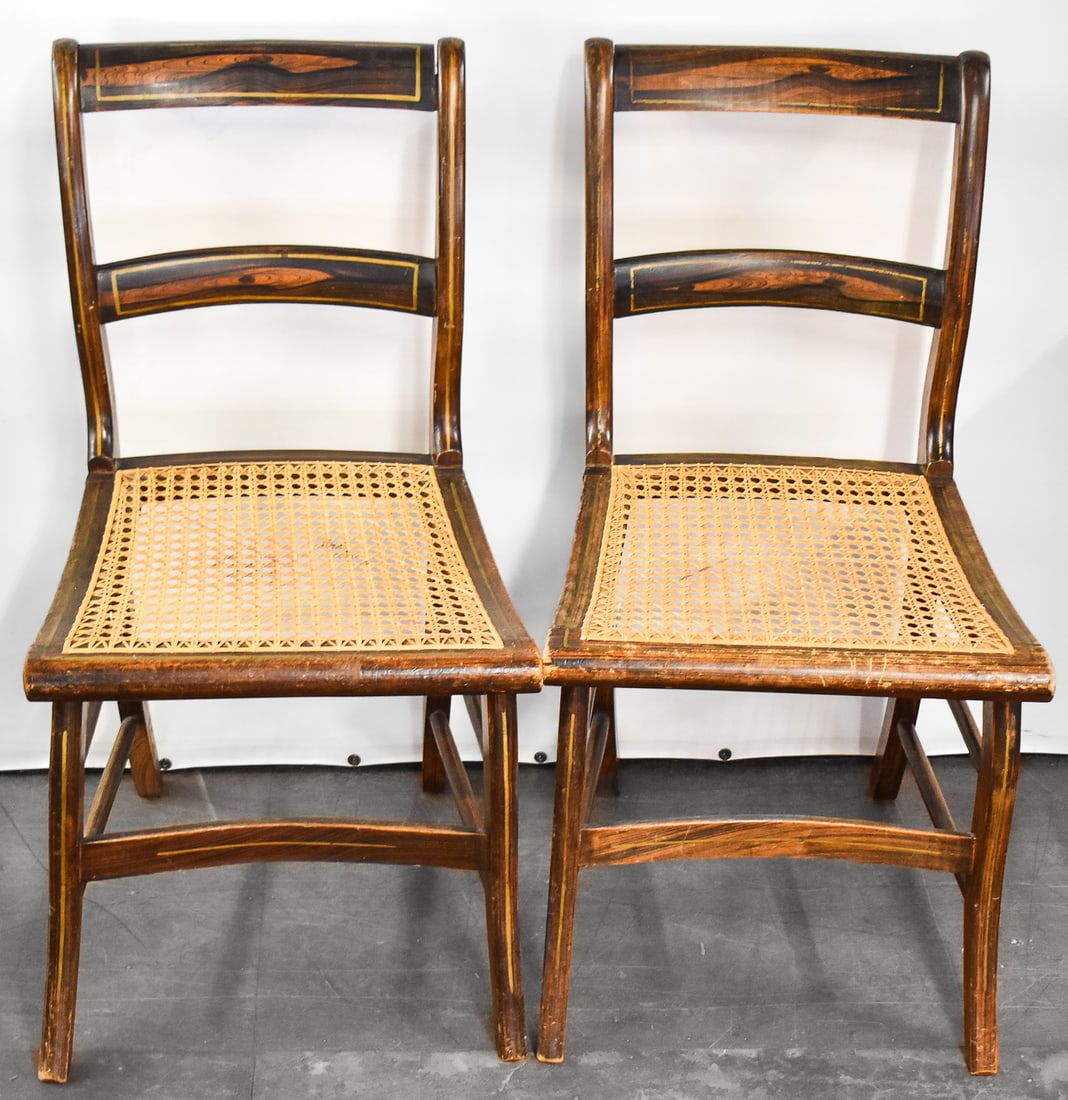 PAIR OF CANE-SEAT WOOD CHAIRS, C. 1860s: A pair of wood cane-seat chair circa 1860's. The chairs feature a dark and light wood pattern with wood inlay accents. Each chair measures 32.5" H x 17.5" W x 20" D.