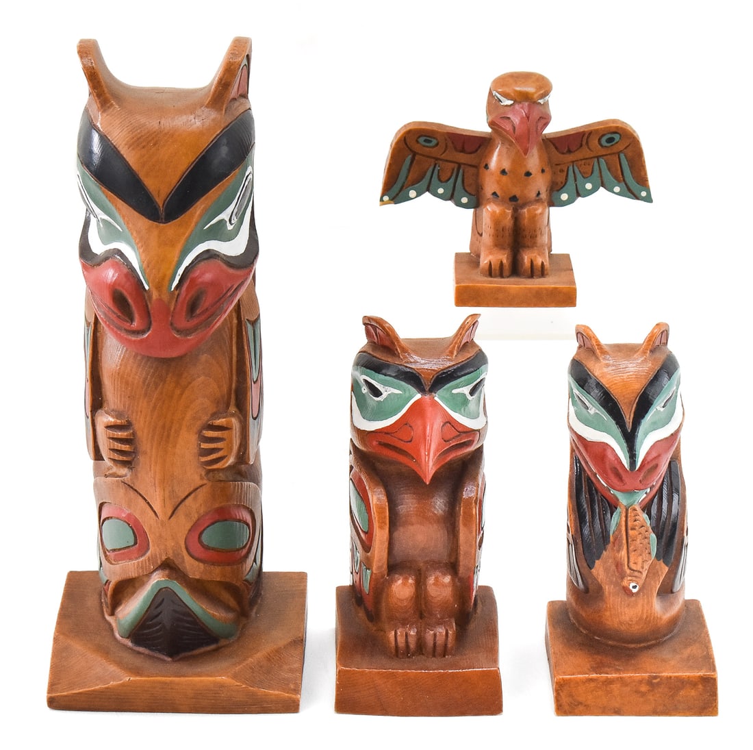 FOUR CONTEMPORARY CANADIAN NORTHWEST COAST STYLE PEARLITE TOTEM POLE SOUVENIRS: Four contemporary Canadian Northwest Coast tribal style Pearlite hand-painted totem pole souvenirs. The largest item measures 10" H, 4" W, 3.5" D.