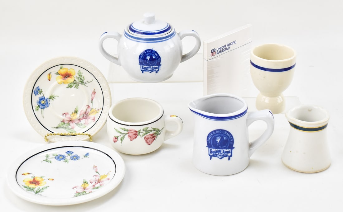 RAILROAD COMPANY GLASSWARE & NOTEPAD: A collection dining service china from various railroad companies and a Union Pacific Railroad notepad in the original packaging. The glassware includes a creamer and lidded sugar bowl from the Denver