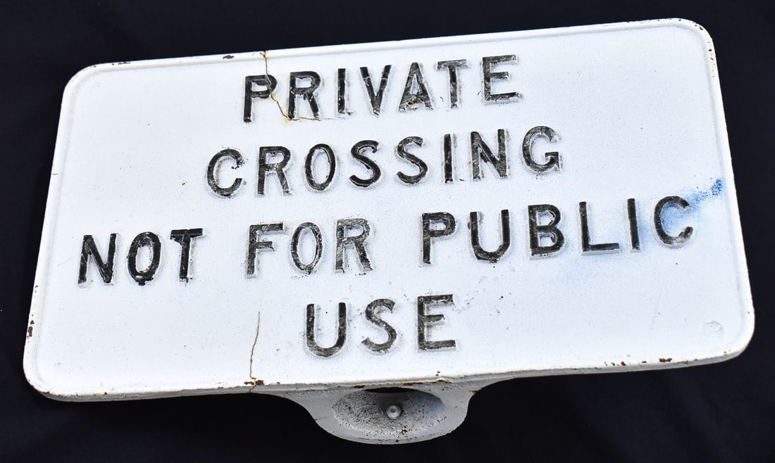 PRIVATE CROSSING POST SIGN: Cast iron sign designed to be bolted to a pole for display. Sign reads " PRIVATE CROSSING NOT FOR PUBLIC USE". Sign has the measurements of 9" H x 15.25" W x 4" D.
