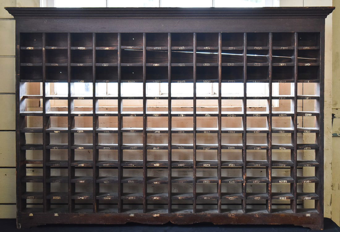 POST OFFICE LETTER SORTER CABINET: Cabinet appears to be made of oak with remnants of previous unit numbers from the mail sorting process. Cabinet measures 39" H x 55.25" W x 6" D.