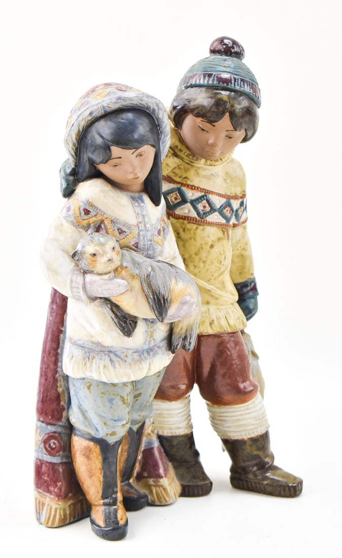 LLADRO 'ARTIC ALLIES' MODEL 2227: A Lladro model 2227 "Arctic Allies" porcelain figurine featuring a boy and girl in traditional Inuit attire holding a seal cub.The figure measures approximately 12" H x 7" W x 4" D.
