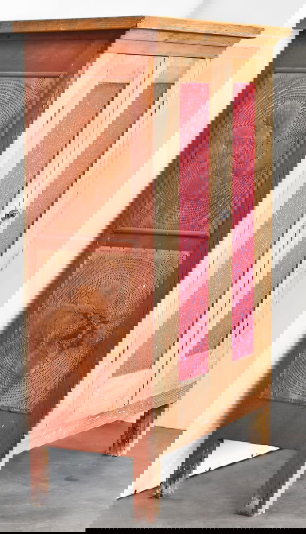 PRIMITIVE PUNCHED TIN PIE CUPBOARD: A red-painted punched tin pie cupboard with two shelves, circa turn of the 19th century. The item measures 61.5" H, 40" W, 20.5" D.