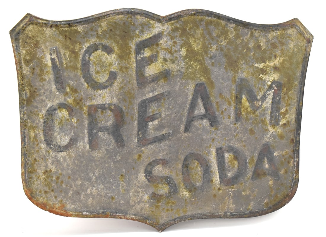 EARLY 20TH CENTURY 'ICE CREAM SODA' EMBOSSED METAL SHIELD SIGN: An "Ice Cream Soda" embossed metal shield advertising sign, circa early 20th century. The item measures 19.5" H, 24" W, 0.5" D.