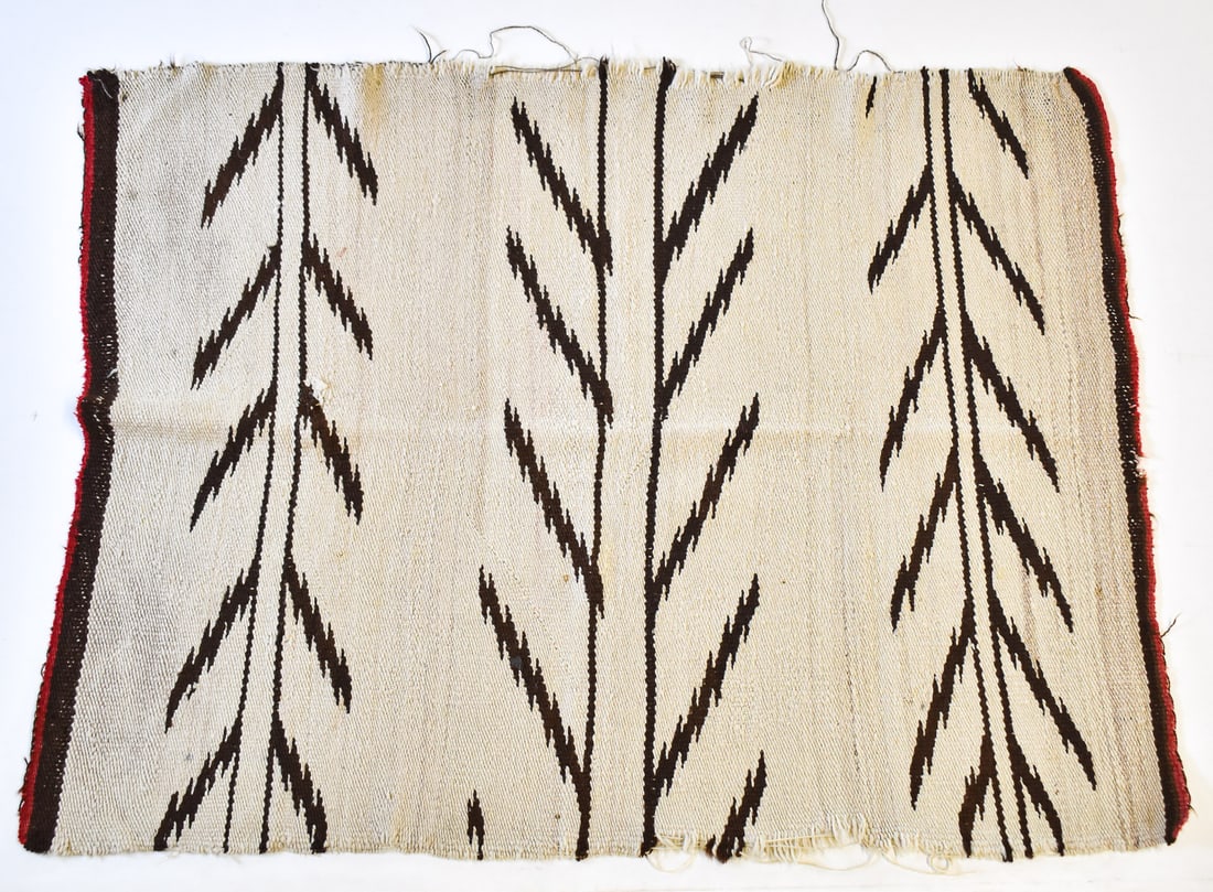 ANTIQUE HANDWOVEN WOOL NAVAJO RUG: An antique handwoven wool Navajo rug with a geometric leaf design. the rug measures 53" H x 40" W x 0.25" D.