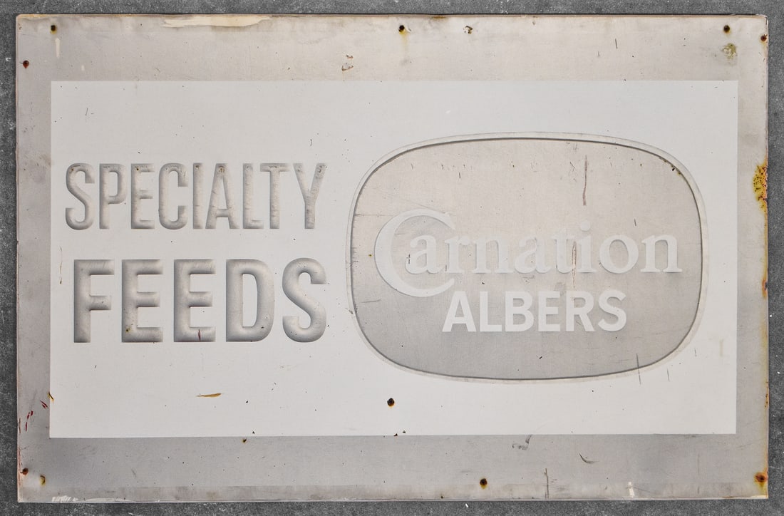 CARNATION ALBERS 'SPECIALTY FEEDS' EMBOSSED ADVERTISING SIGN: A Carnation Albers "Specialty Feeds" embossed metal sign over wood, circa early-mid 20th century. The item measures 30" H, 46" W, 1" D.