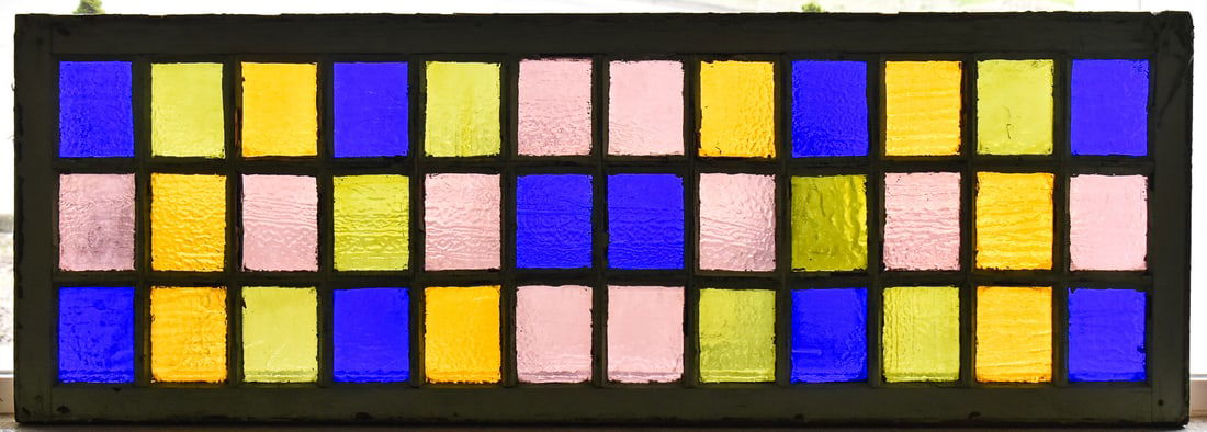 MULTI-COLORED GLASS DOOR PANEL: A multi-colored glass architectural door panel with green painted wood trim, measuring 57" H x 20" W x 1.5" D.