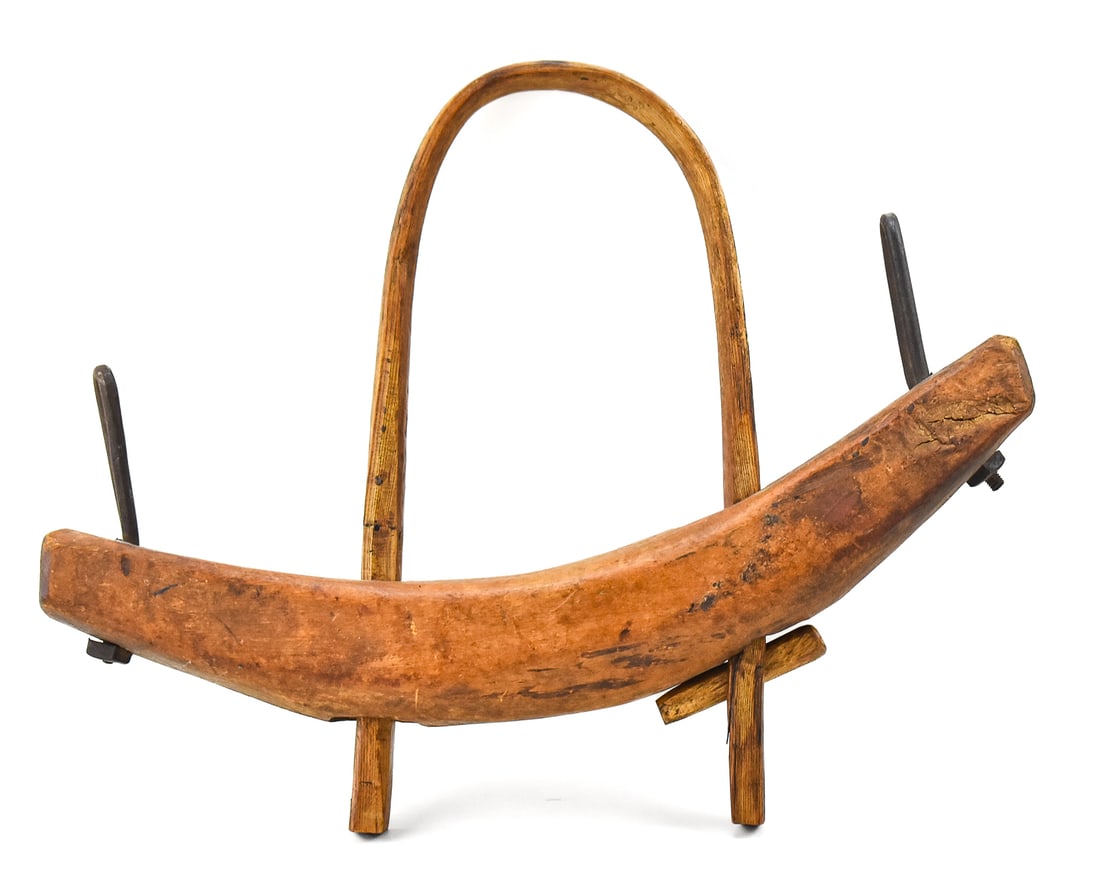 SINGLE NECK-BOW OX YOKE PLOW COLLAR; 19TH CENTURY: A wooden single neck-bow ox yoke plow collar with iron hardware, circa 19th century. The item measures 5" H, 24" W, 18.5" D.