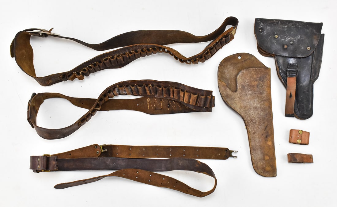 LEATHER HOLSTERS & BULLET BANDOLIERS: An assortment of antique leather holsters an bullet bandoliers including a tan leather revolver holster, a black leather pistol holster with leather clover, and two brown leather bullet bandoliers.