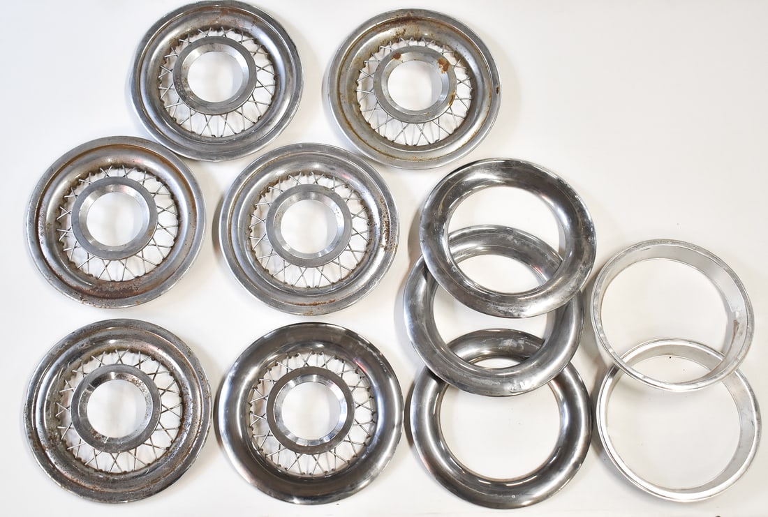 ASSORTMENT OF STAINLESS STEEL WHEEL COVERS: An assortment of stainless steel vintage car wheel covers. Six wire wheel covers, and five wheel trims. Each wired wheel cover measures 17" H x 17" W x 2.5" D.
