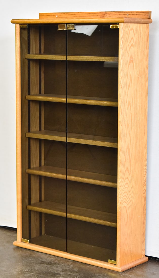 GLASS DOOR WOOD VERTICAL DISPLAY CASE WITH SHELVES: A vertical wood display case with two smokey glass doors and five adjustable wood shelves. The display case measures 43" H x 23.5" W x 8" D.