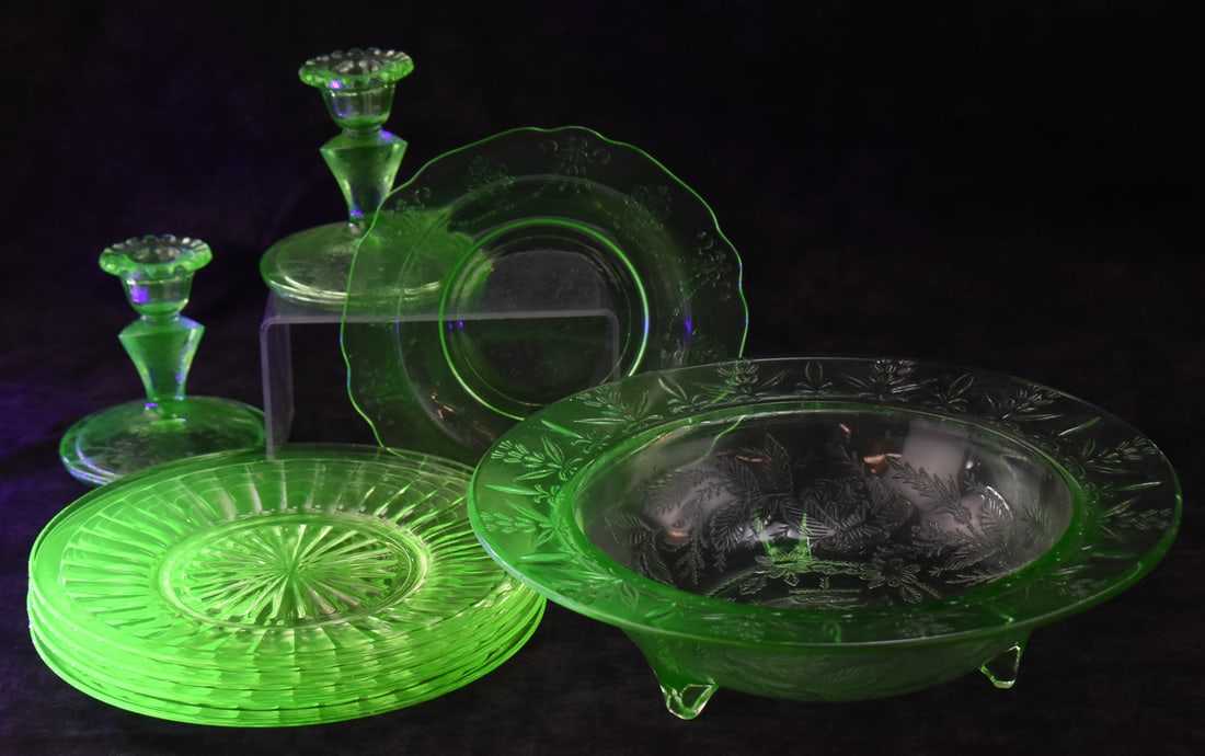 VINTAGE GREEN URANIUM GLASS COLLECTION: A vintage green uranium glass collection which includes, one "Bow Knot" salad plate, four "Pillar Optic" luncheon plates, a set of candle holders, and a 1930s "Rose & Thorn" pattern rimmed serving