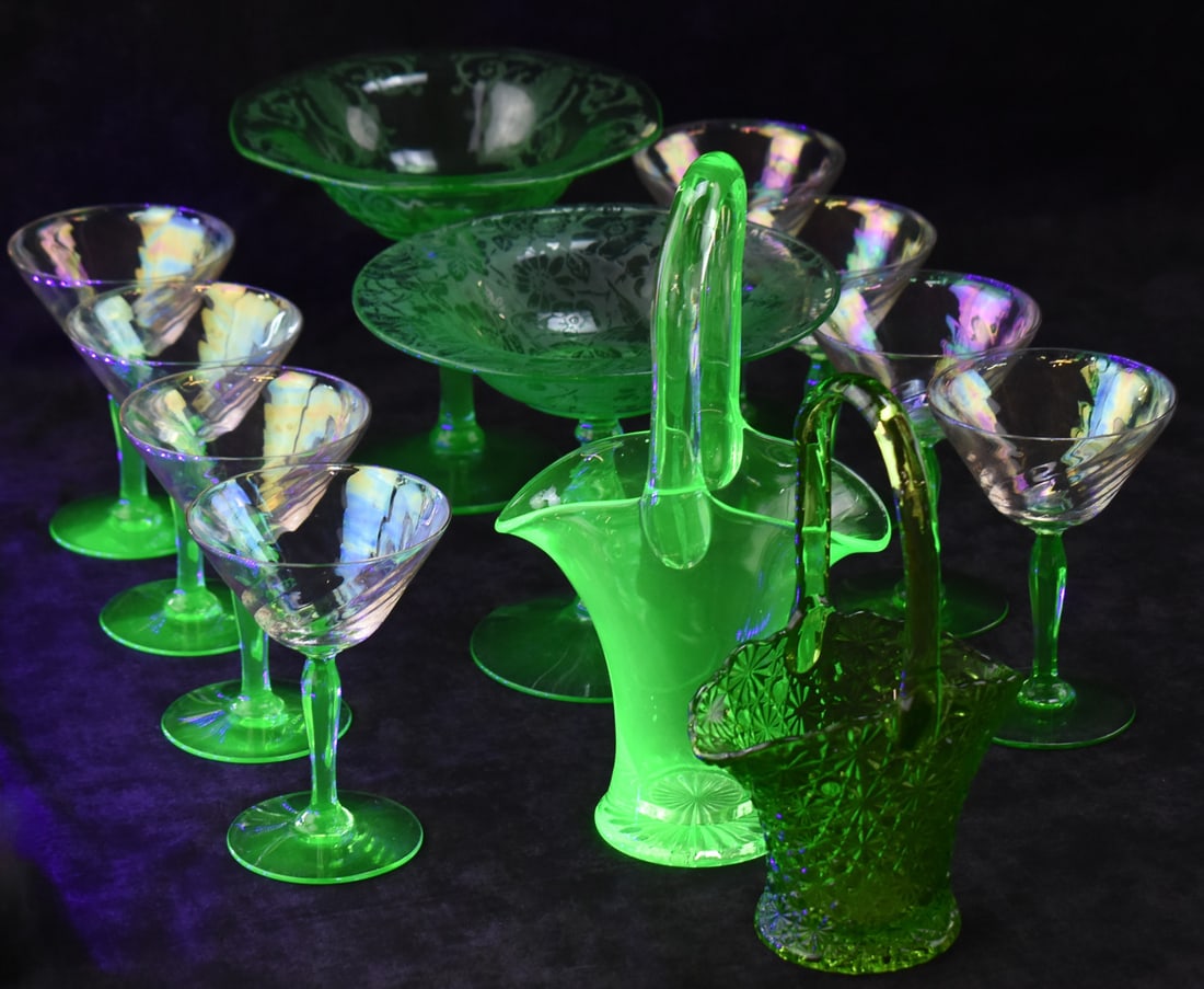 URANIUM & GREEN GLASS ASSORTMENT: FOSTORIA, FENTON, & TIFFIN: An assortment of uranium and green glass including a set of eight Fostoria "Swirl Optic" green uranium glass stem cocktail glasses, two Fostoria uranium glass footed compotes, one in the "Versailles" 