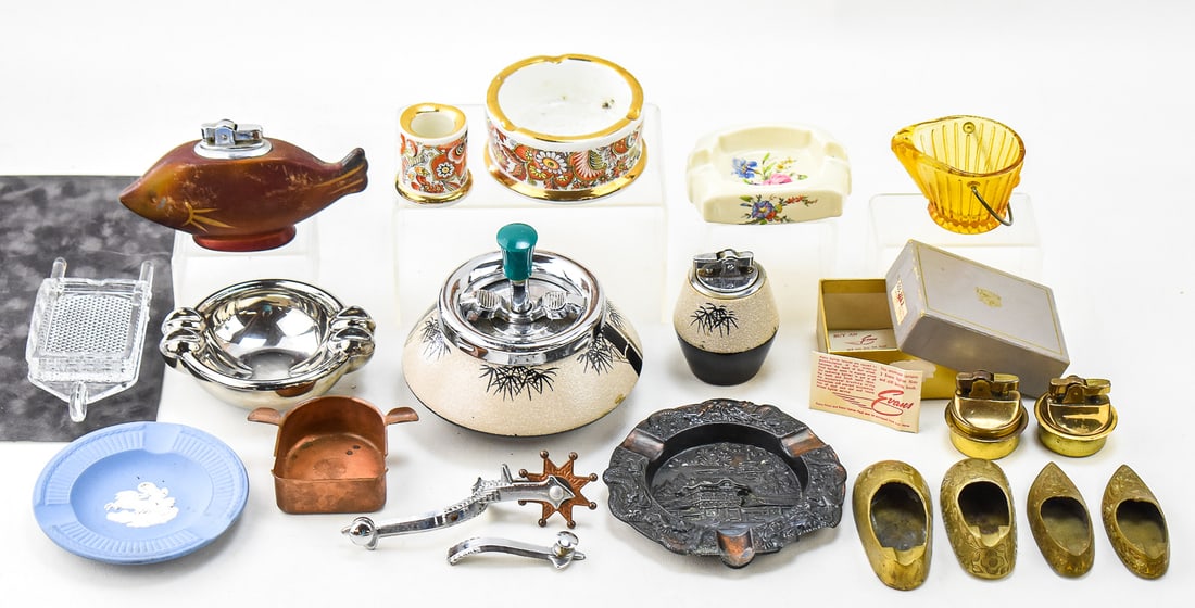 20TH CENTURY ASHTRAYS AND TABLE LIGHTERS: WEDGWOOD, GUARDSMAN, LE SMITH (ATTR.), & MORE: This lot includes the following, circa 20th century: Wedgwood ashtray, Japanese smoking set, Japanese fish-form table lighter, Japanese repousse souvenir ashtray, Indian slipper ashtrays, Grecian cera