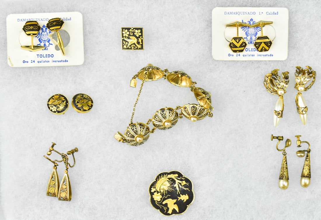 DAMASQUINADO 24K GOLD INLAID JEWELRY, TOLEDO, SPAIN: A collection of Damasquinado crafted 24K gold inlaid jewelry originating from Toledo Spain. The lot includes six pairs of earrings of different styles, a single earring, a brooch, and an ornate bracel