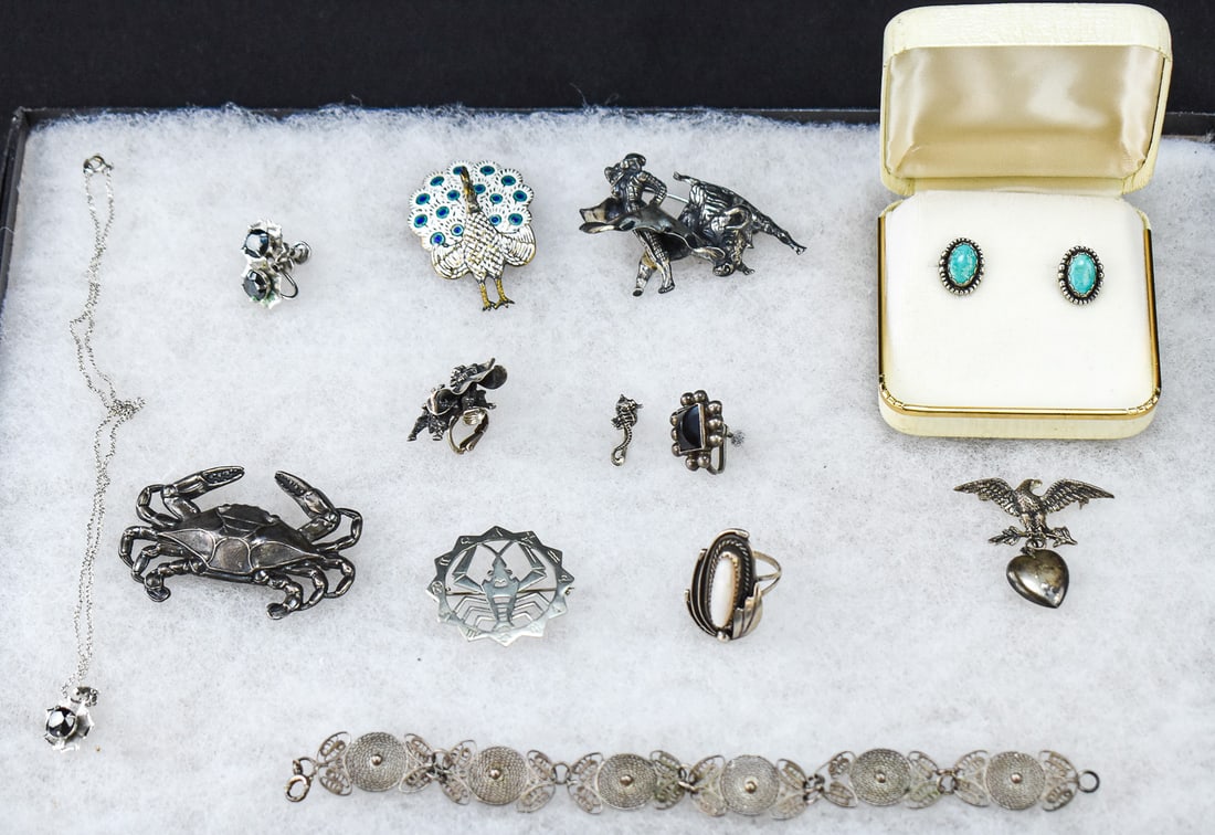ASSORTMENT OF SILVER-TONE & STERLING SILVER JEWELRY: An assortment of jewelry, some of which is marked sterling silver including brooches, bracelets, earrings, and a necklace. One set of earrings and the necklace are marked sterling silver, however they