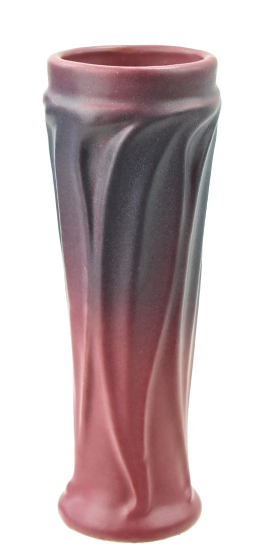 VAN BRIGGLE SWIRLED VERTICAL LEAF-PATTERN MULBERRY VASE: A Van Briggle marked swirled vertical leaf-patterned vase in mulberry glaze, circa 1911. The item measures 8" H, 3" W, 3" D.