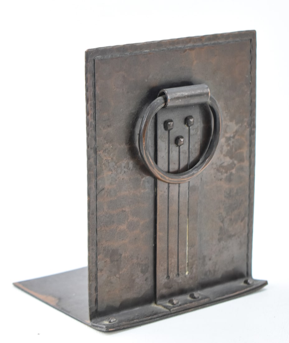 ROYCROFT ARTS AND CRAFTS COPPER BOOKEND: An Arts and Crafts copper bookend made by Roycroft, circa early 1910-1915. The bookend is made of hand-hammered copper with decorative rivets on the center and base and a decorative ring. The bookend