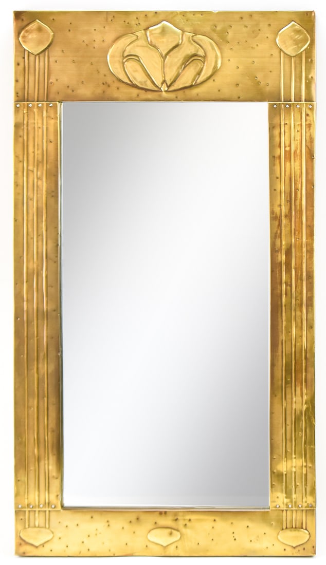 ENGLISH ARTS AND CRAFTS HAMMERED BRASS WALL MIRROR: An English Arts and Crafts hammered brass wall mirror, circa early 20th century. The item measures 33.5" H, 18.5" W, 1" D.
