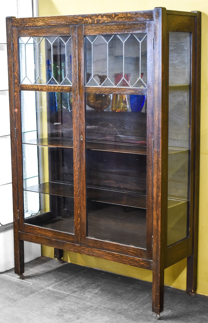 ARTS AND CRAFTS MISSION OAK CHINA CABINET: An Arts and Crafts Mission oak china cabinet on casters with lead framed panels and four shelves, circa early 20th century. The item measures 62" H, 41.5" W, 16" D.
