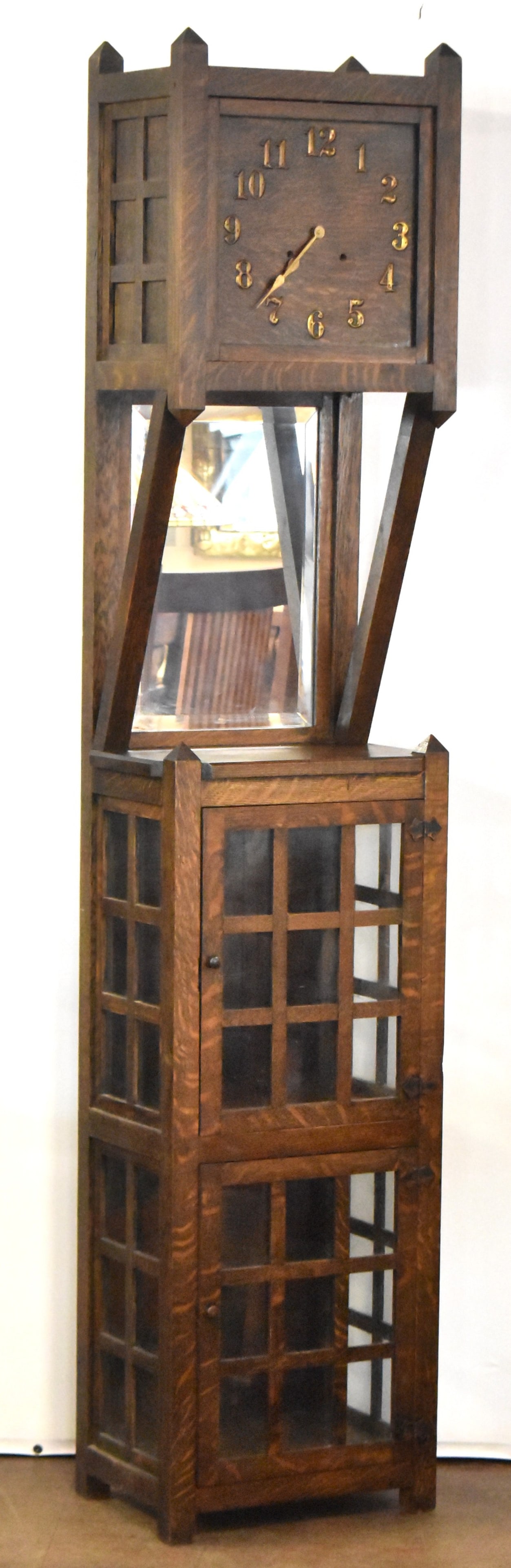 MISSION ARTS AND CRAFTS OAK GRANDFATHER CLOCK: A Mission Arts and Crafts grandfather clock with central mirror and two lower glass cabinets, circa early 20th century. The item measures 80" H, 17.5" W, 12.5" D.