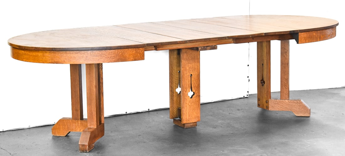 ARTS AND CRAFTS STICKLEY STYLE QUATER-SAWN OAK DINING TABLE WITH FOUR LEAVES: An Arts and Crafts Stickley style quarter-sawn oak dining table with four leaves and trestle legs with cut-out designs, circa early 1900s. The table including the leaves measures 28" H x 45" W x 104" 