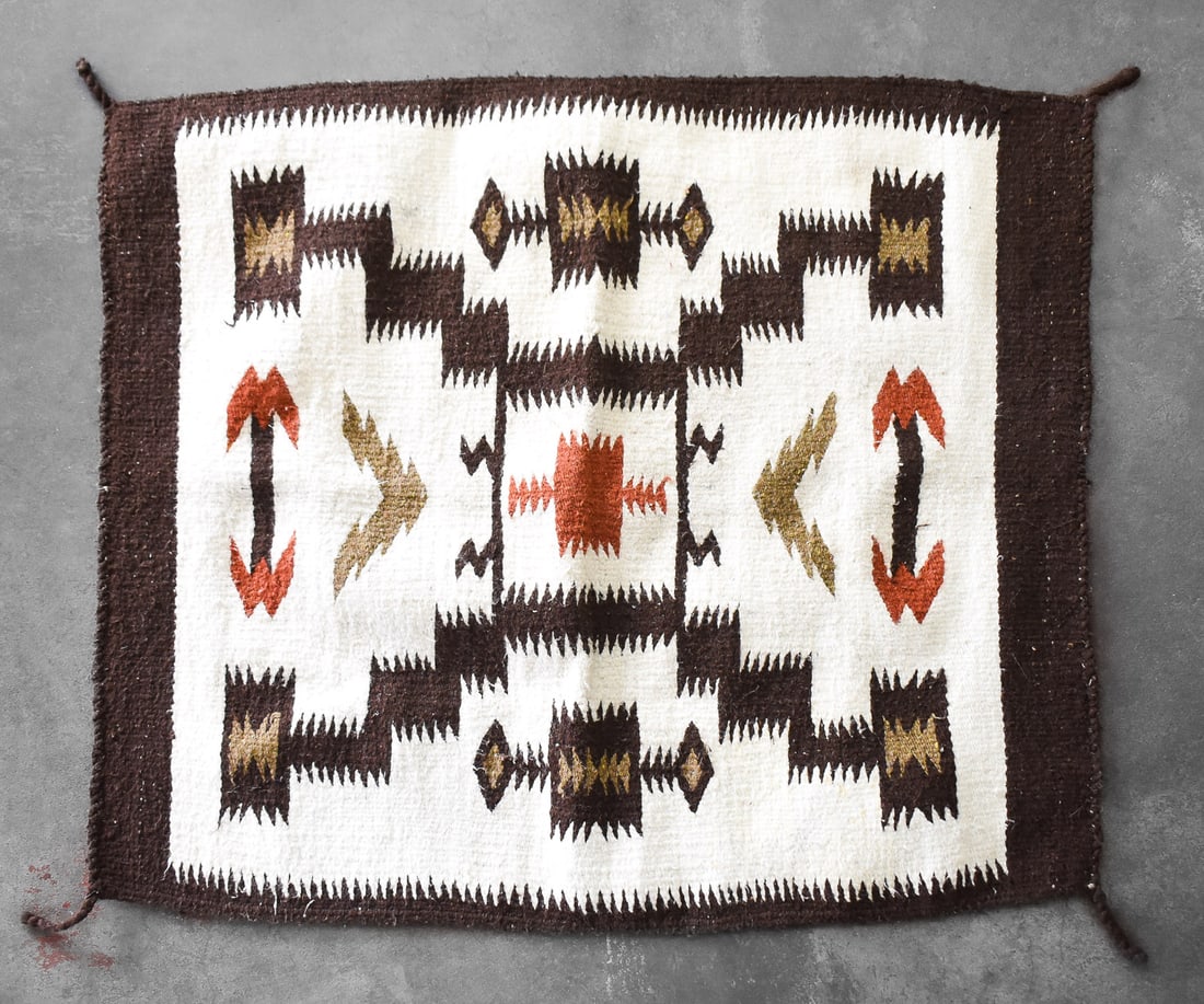 NAVAJO STYLE 'STORM' RUG: Rug depicts the pattern known as "storm". The center square represents the universe with the radiating lines representing lighting. The textile has many earth tone colors through out it. Rug has the m