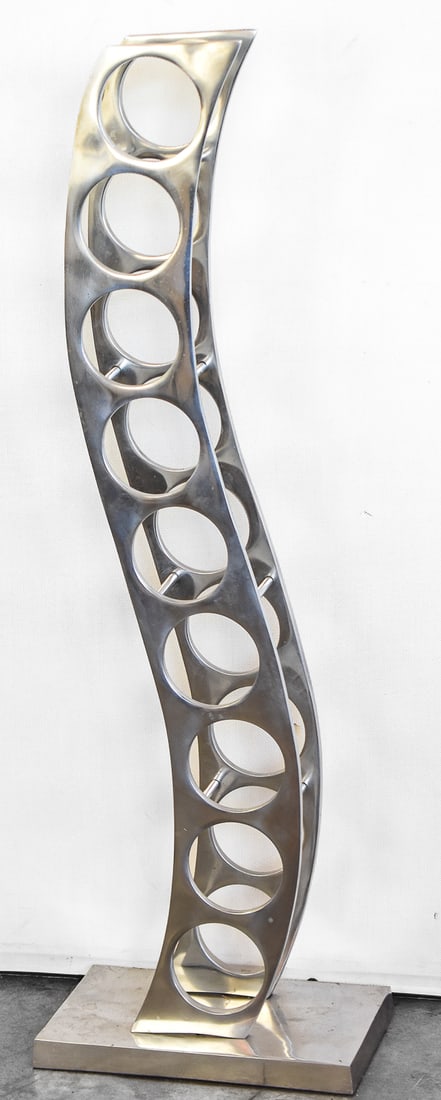 POLISHED ALUMINUM FLOOR-STANDING WINE RACK: A polished aluminum modern style floor-standing wine rack with a sculptural 'S' curve and an aluminum base, with room for nine wine bottles. The wine rack measures 14" H x 13.5" W x 8" D.