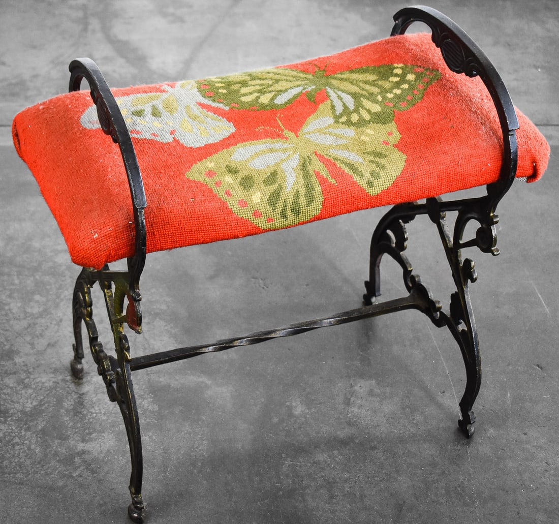 CAST IRON BOUDOIR BENCH: A cast iron boudoir bench with a needlepoint butterfly motif, circa early 20th century. Measures 21" H x 22.5" W x 12" D.