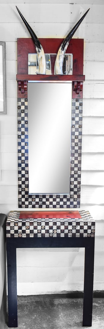 CHECKERED CONSOLE AND HORN MIRROR SET: A checkered designed wall console and wall mirror with a pair of horns decorating the crown. The mirror measures 47" H x 18" W x 4" D and the wall console measures 30" H x 23" W x 11" D.