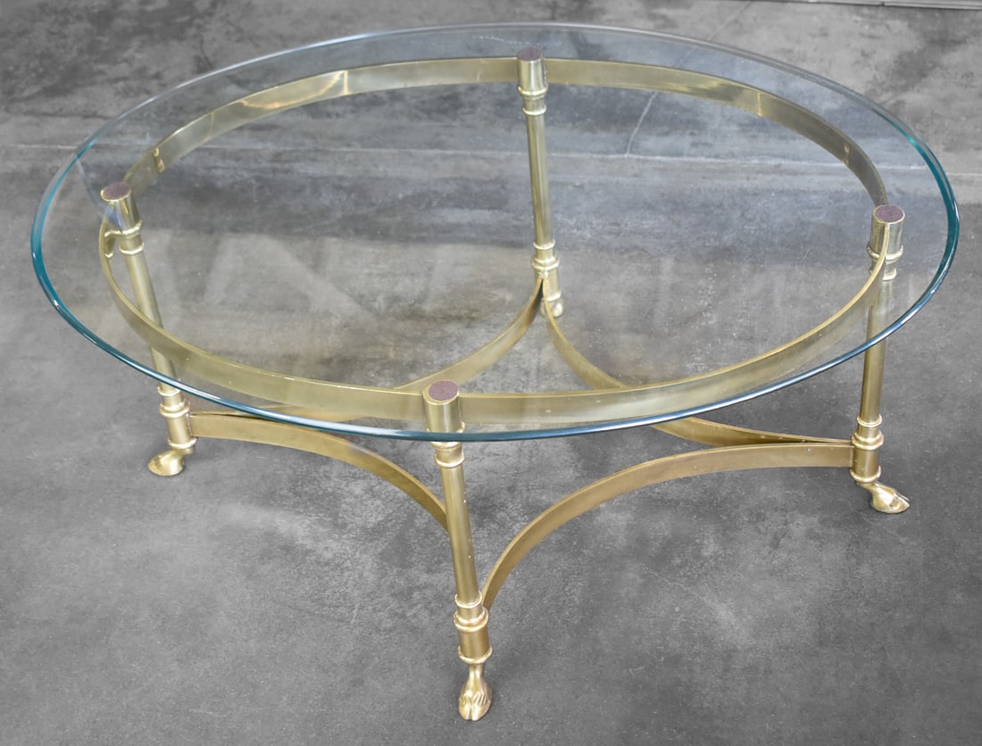 LABARGE HOLLYWOOD REGENCY BRASS & GLASS HOOVED FEET COFFEE TABLE: A Hollywood Regency brass base and glass top coffee table with four hooved deer feet legs, made by LaBarge circa 1960s. The table measures 15.5" H x 30.5" W x 22" D.