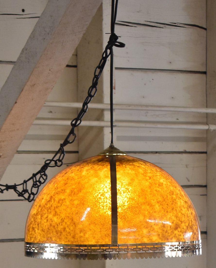 MID-CENTURY MODERN SWAG LAMP: A Mid-century Modern swag lamp with a yellow and amber speckled acrylic shade and brass bands with a cut-out brass rim, circa 1960-1970s. The lamp measures 12" H x 18" W x 18" D.
