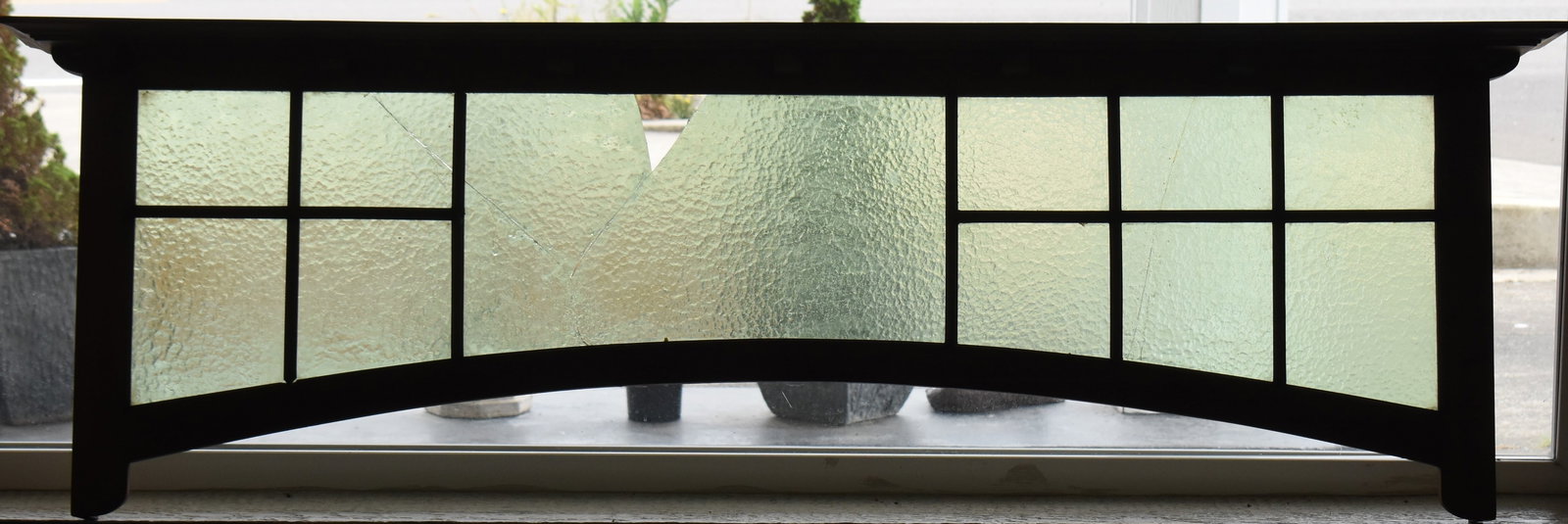 ARTS AND CRAFTS STYLE ARCHED TRANSOM WINDOW: An Arts and Crafts style arched transom window with green textured glass panels, circa early 20th century. The item measures 22.5" H, 70" W, 7" D.