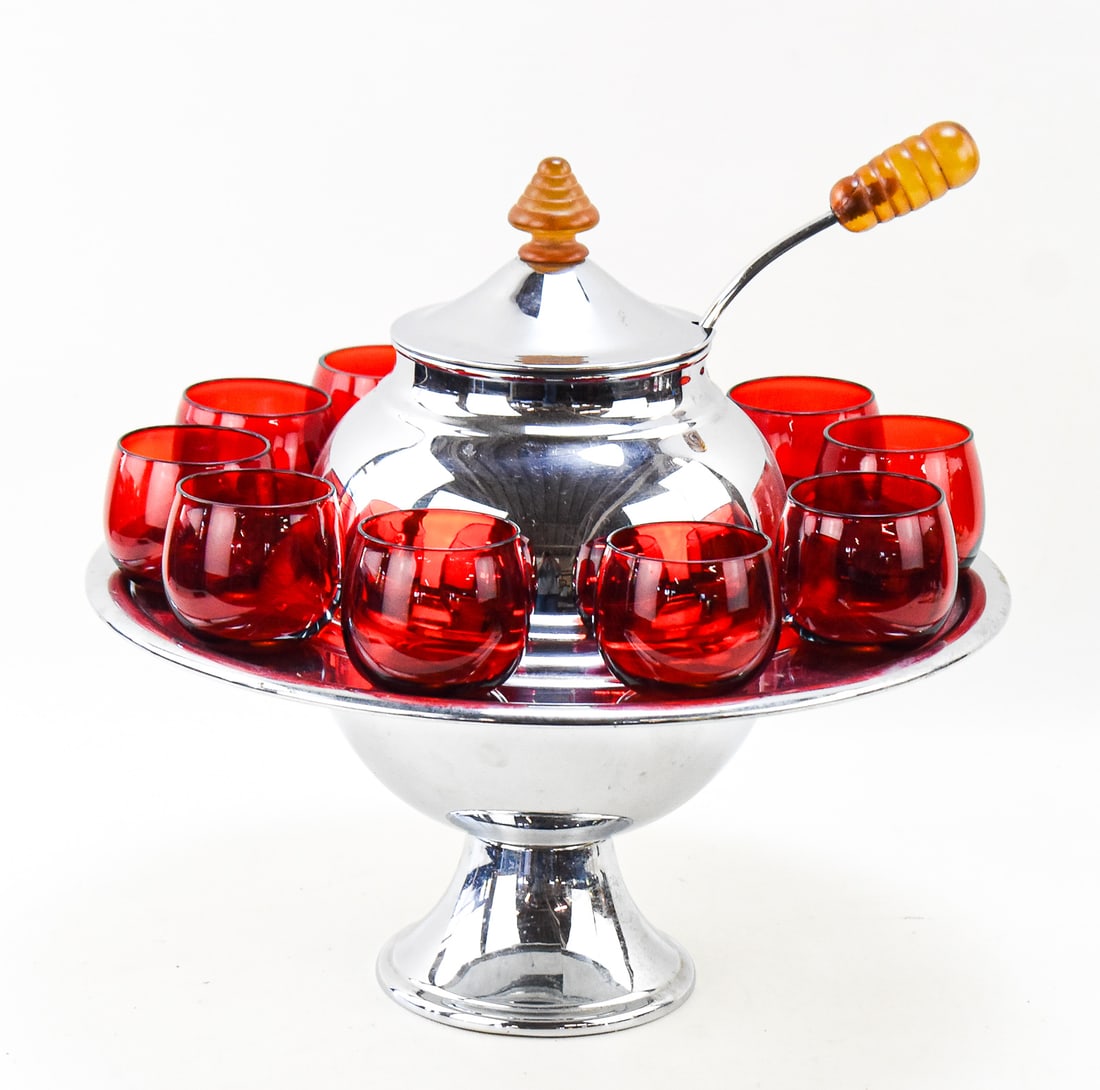 LEHMAN BROTHERS CHROME SATURN PUNCH BOWL WITH CUPS: A Lehman Brothers chrome and lucite Saturn punch bowl with ten ruby red glass cups, circa early 20th century. The largest item measures 14" H, 15" W, 15" D.