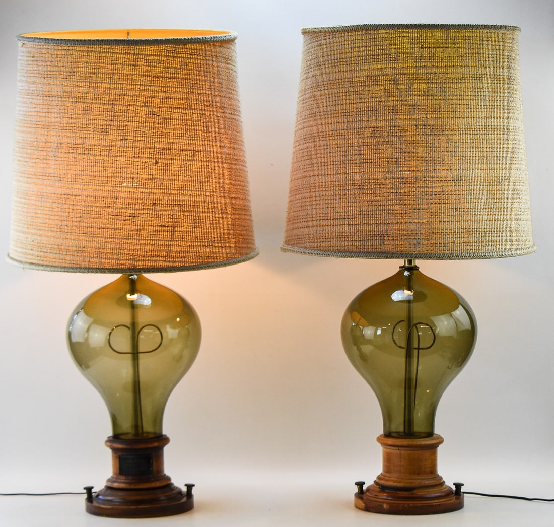 PAIR OF MID-CENTURY MODERN OVERSIZED EDISON LIGHTBULB TABLE LAMPS: A pair of Mid-century Modern style table lamps featuring a smokey glass base and in the design of an oversized Edison bulb. Each lamp base is in the style of the original Edison bulb base, and they