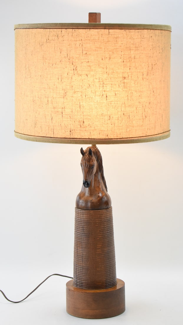 AUGUST BRANDT FOR RANCH OAK FURNITURE CO., CARVED OAK HORSE TABLE LAMP: A carved oak horse table lamp made by August Brandt for Ranch Oak Furniture Company, circa 1950s. The lamp includes a drum shape period burlap shade. The lamp measures 31.5" H x 17.5" W x 17.5" D.