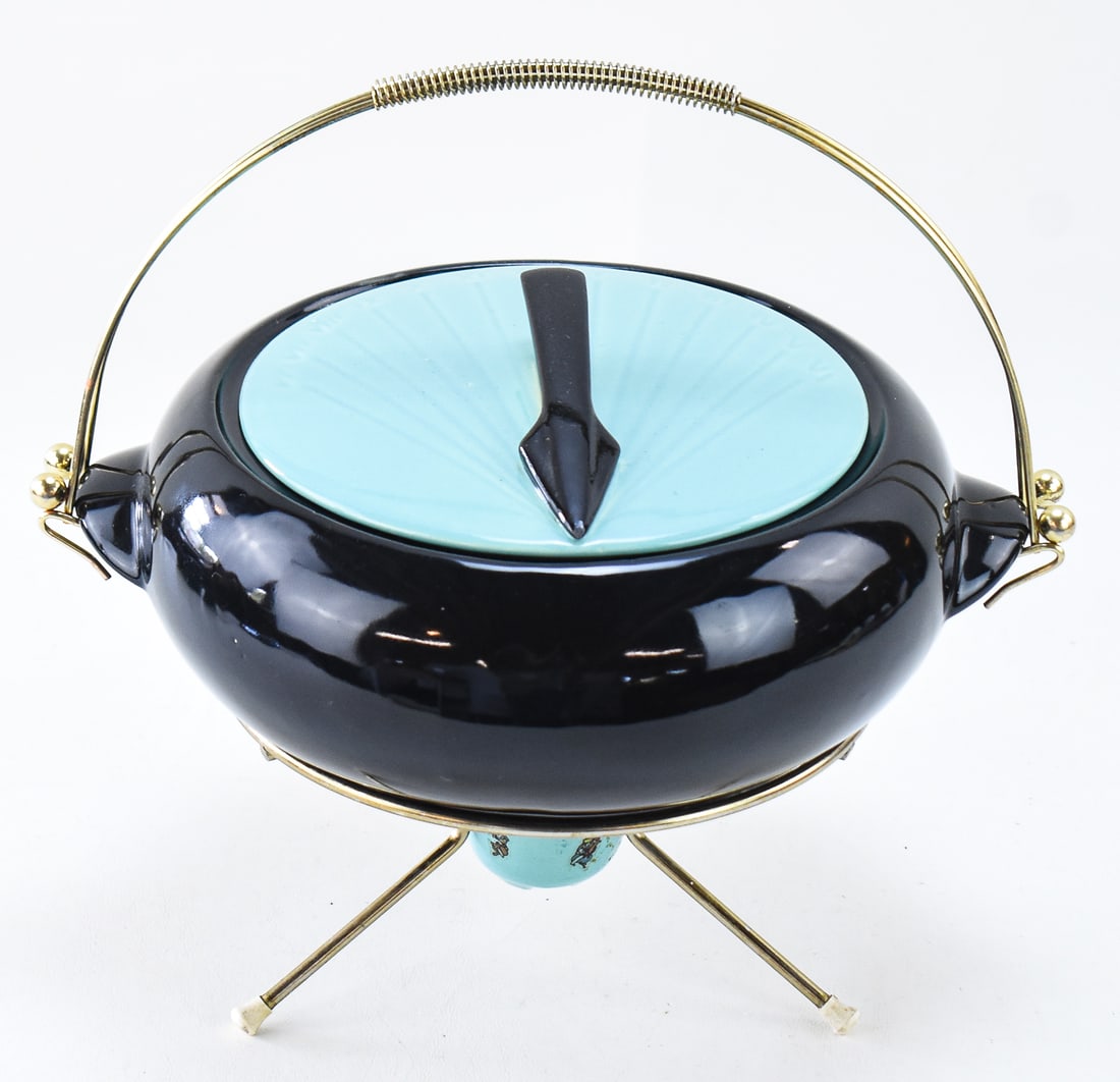 MID-CENTURY ATOMIC-STYLE SHAWNEE POTTERY KENWOOD LIDDED 'SUNDIAL' DISH WITH STAND: A Mid-century Atomic style Shawnee Pottery Kenwood lidded "Sundial" dish with a handled warming stand. Measures 12" H x 11.5" W x 9" D with the stand.