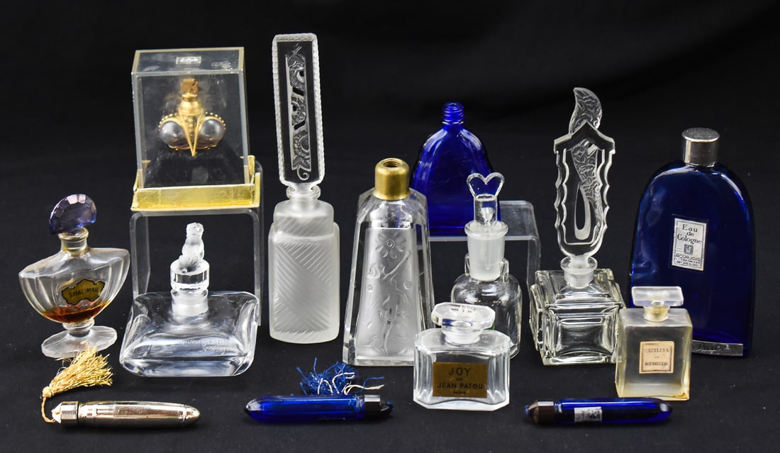 ASSORTMENT OF PERFUME BOTTLES: An assortment of fourteen perfume bottles from multiple brands with a variety of styles. Most of the bottles are empty. The tallest perfume bottle measures 6.5" H x 2" W x 2" D.