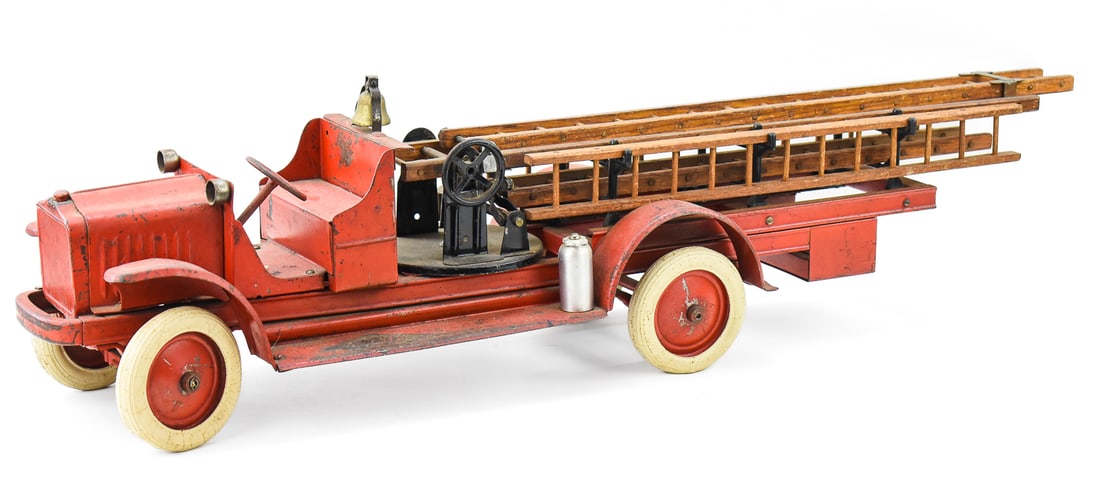 KELMET 'WHITE' PRESSED STEEL 'BIG BOY' AERIAL LADDER FIRE ENGINE TRUCK: A Kelmet Corporation "White" pressed steel "Big Boy" aerial ladder fire engine truck with wooden ladders, rubber tires, and replacement fire extinguishers circa 1920s. The item measures 9.5" H, 7.5" W