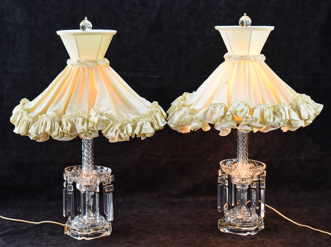 PAIR OF CUT CRYSTAL HOLLYWOOD REGENCY TABLE LAMPS: A pair of Hollywood Regency table lamps made of cut crystal with crystal prisms. Each lamp has a ballerina ruffle lampshade. Each lamp measures 29" H x 20" W x 20" D.