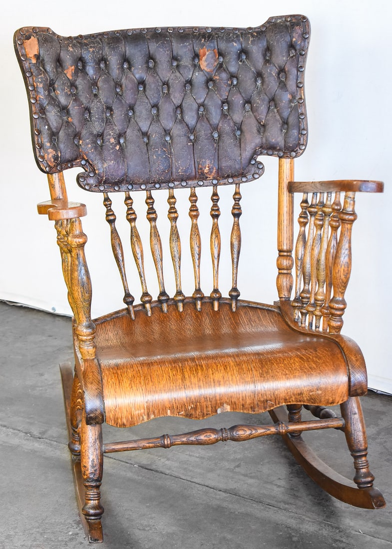 AMERICAN OAK ROCKING CHAIR: Constructed from tiger oak, a tooled leather back and brass pins. Built in the late 19th to early 20th century, this rocking chair measures approx. 35" H x 24.5" W x 36" D.