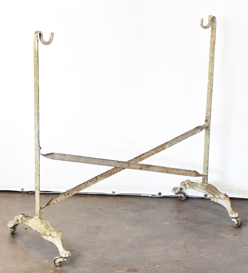 VICTORIAN WROUGHT IRON SWINGING CRADLE STAND: A late 1800s wrought iron swinging cradle stand on castors. It measures approx. 33" H x 35" W x 17.5" D.