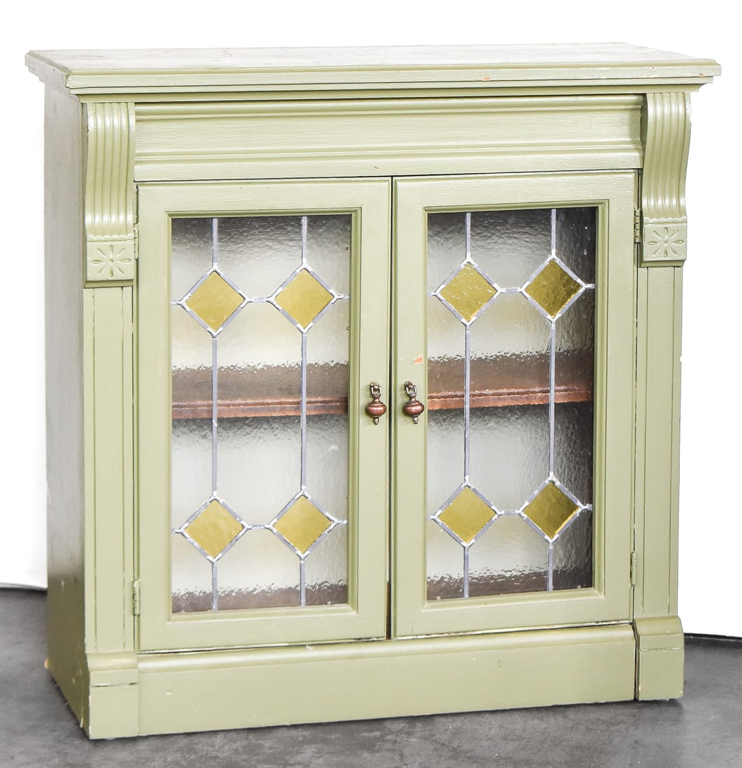 GREEN PAINTED WOOD CABINET WITH LEADED GLASS PANEL DOORS: A painted green cabinet with natural wood interior. The doors have leaded stained glass panels with a diamond design. The cabinet measures approx. 31" H x 31" W x 13" D.