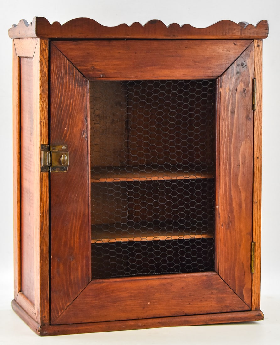 RUSTIC HANGING CABINET: The cabinet is made of solid wood with a chicken wire front door. The door is held closed with a brass latch. The cabinet is from the 19th century and measures approx. 25.5" H x 19.5" W x 10" D.