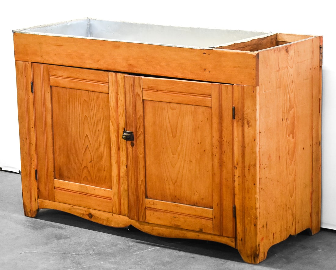 PRIMITIVE DRY SINK: A circa early 1800s primitive pine dry sink . It is lined with a zinc basin and has cabinet doors and shelves inside. The sink measures approx. 32" H x 37.5" W x 19" D.