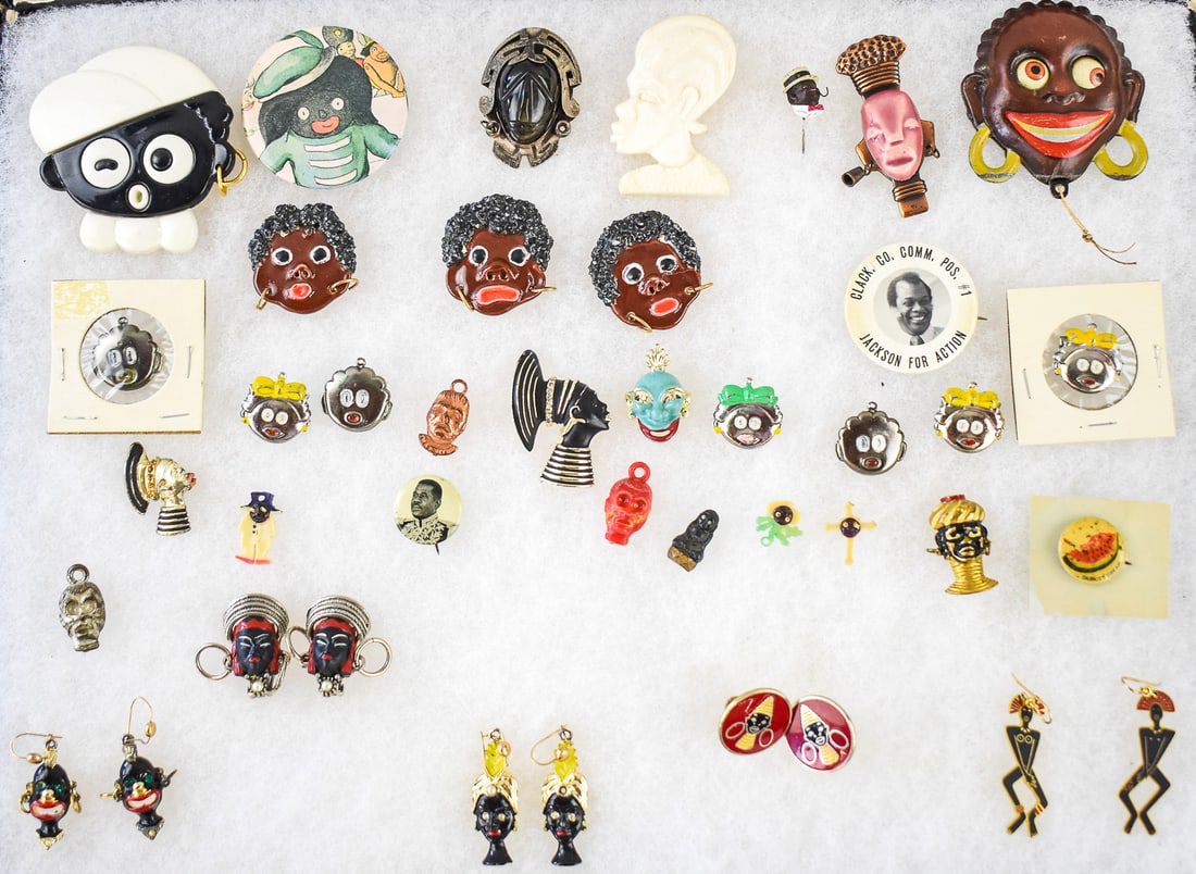 ASSORTMENT OF BLACK AMERICANA AND TRIBAL PINS & JEWELRY: TAXCO STERLING SILVER, CORO: A large assortment of Black Americana and Tribal design pins and earrings, including a Taxco sterling silver onyx face pendant marked Taxco .925 on the back, a pair of Coro enameled African Tribal God