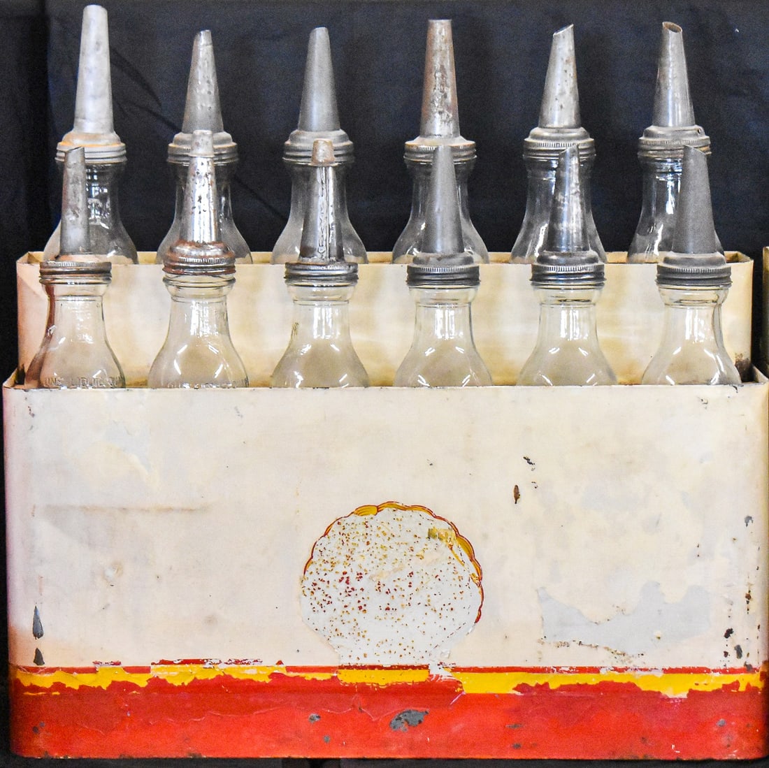 SHELL MOTOR OIL BOTTLE RACK: A Shell branded motor oil bottle rack circa 1930 with all twelve original bottles included. The rack measures approx. 19" H x 29" W x 11" D and the rack with the bottles measures approx. 29" H x 29" W