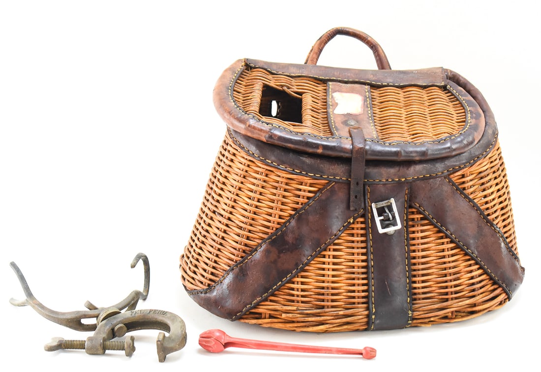 ANTIQUE FISHING CREEL BASKET W/ A & H HOOK REMOVER & BARCO FISHING ROD HOLDER: An antique fishing creel basket made of leather and wicker, an A & H hook remover, and a BARCO clamp fishing rod holder. The fishing creel measures approx. 10" H x 14" W x 7" D.